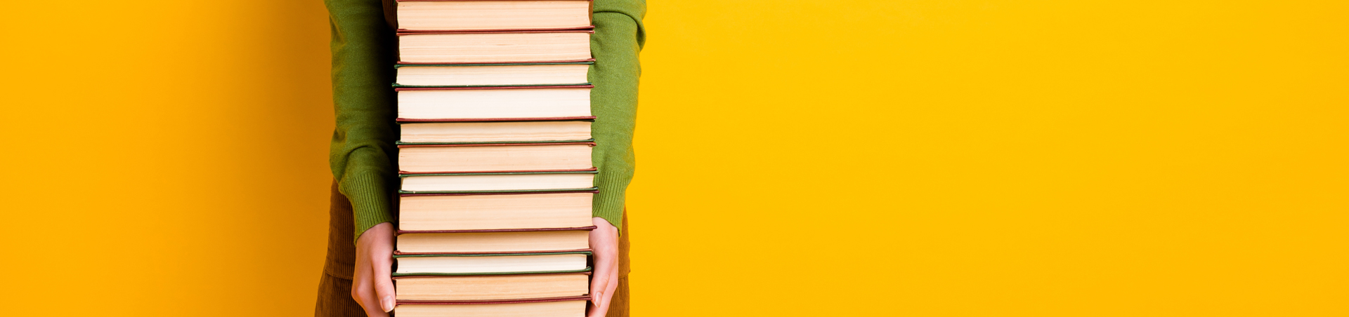 person holding a large stack of books