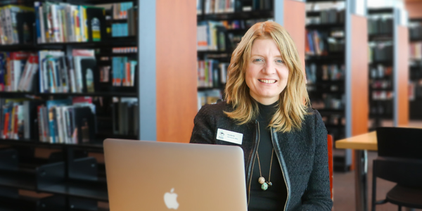 CEO Lita Barrie seated at a table with book shelves in background