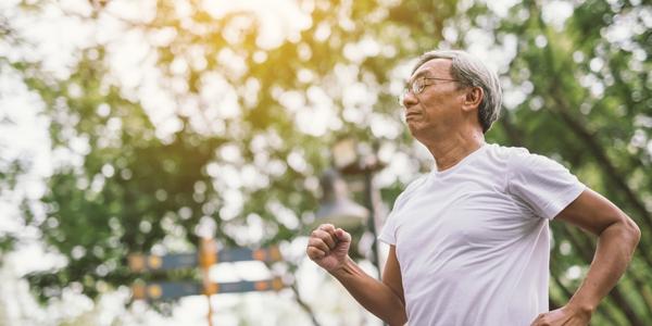 older adult running outside with trees in background