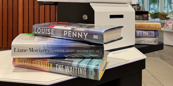 three books stacked on a self-checkout unit.