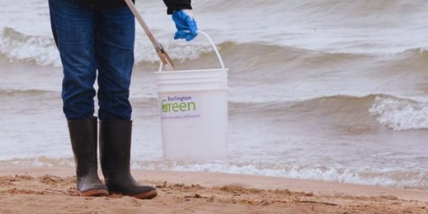 Photo credit: Peter McCusker. Person wearing boots and holding a white bucket and garbage picker