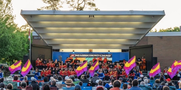 crowd of seated people facing a band playing at the Central Park Music Centre