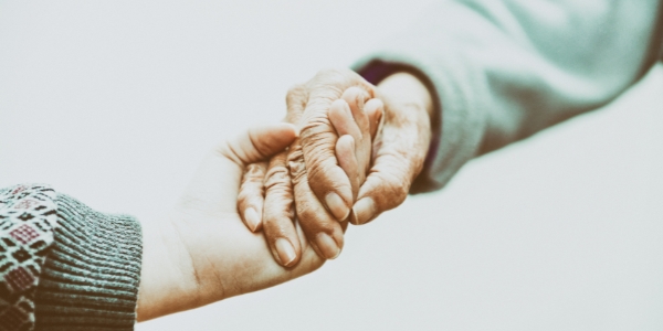 an older hand holding a younger hand