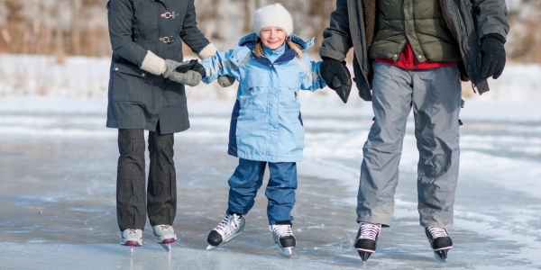 two adults and a child skating at an outdoor rink