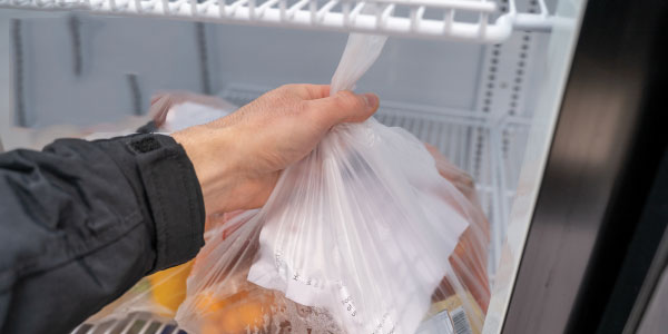 hand reaching for a bag of food in a fridge