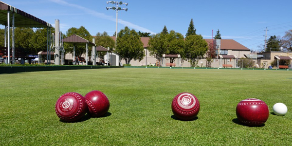 four red lawn bowling balls on a grass field