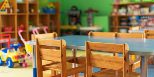 view of a classroom with small table with five chairs and shelves of toys in background