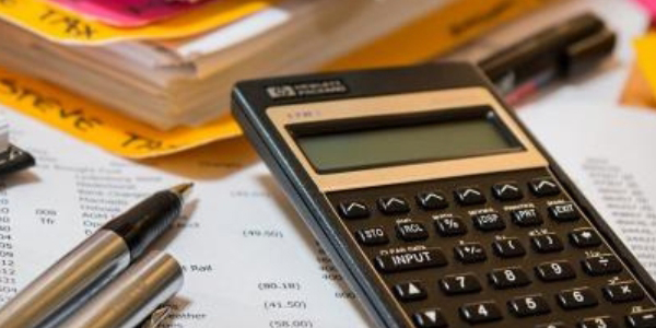 calculator, pen, and file folders resting on a financial spreadsheet