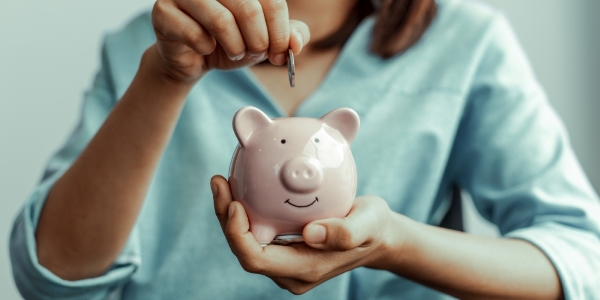 person putting a coin in a piggy bank