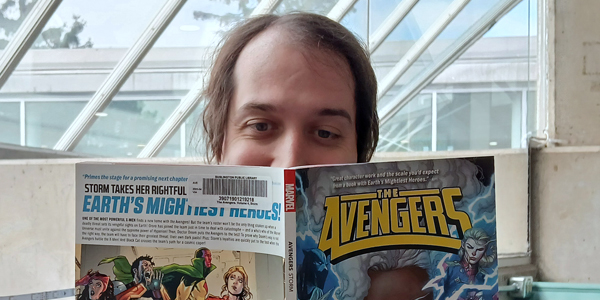 adult holding up a graphic novel The Avengers