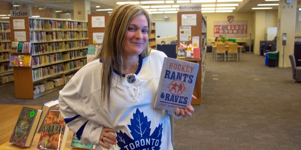 Heather standing in branch holding a copy of the book Hockey Rants & Raves