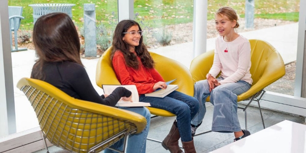 three young adults sitting in chairs socializing