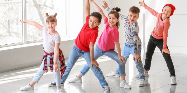 five school age children standing is a line in a dance pose
