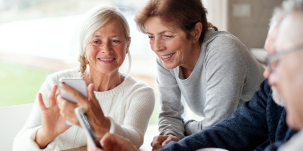 older adults holding tech and talking