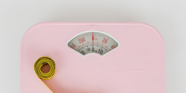 tape measure resting on a pink bathroom scale 
