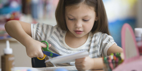 young person using scissors to cut paper