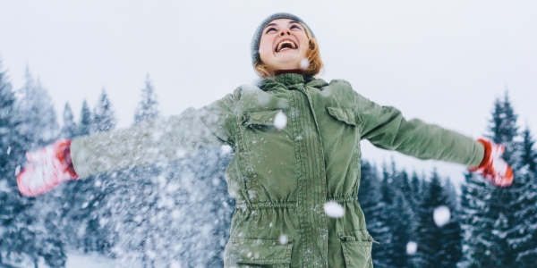 adult standing outside in winter with arms outstretched 