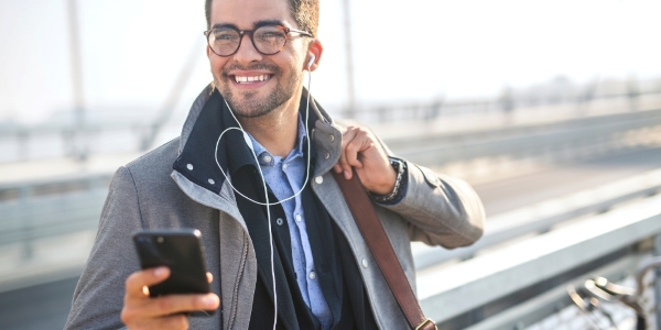 adult holding a mobile phone and wearing earphones