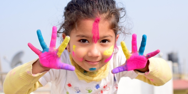 child with paint on their hands smiling at the camera