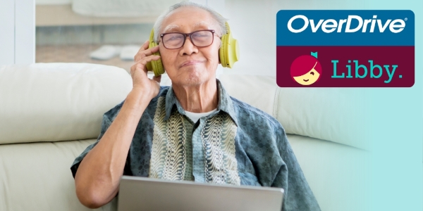 senior adult holding a laptop and wearing headphones while sitting o