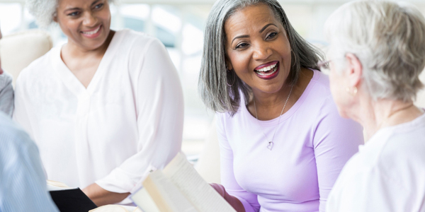 A group of older adults laughing with books in their hands