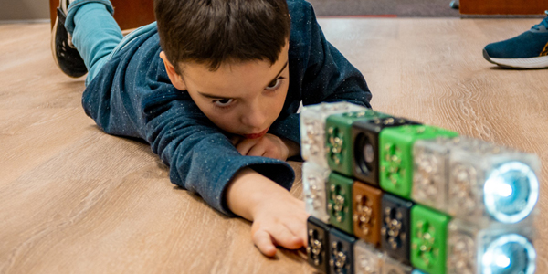 child laying on the floor working with cubelets