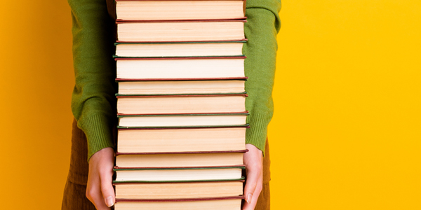 person holding a large stack of books