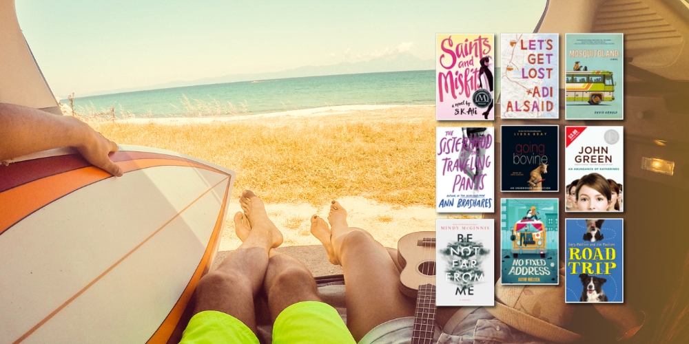 view of a beach looking outside from inside the back of a car with a surfboard and the legs of people lounging