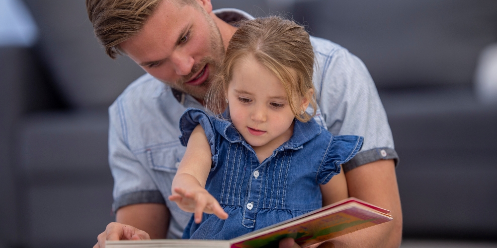 adult sharing a picture books with a young child