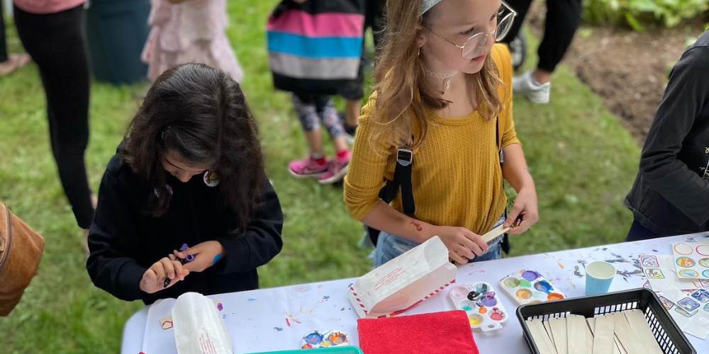 Two young girls colour wooden bookmarks