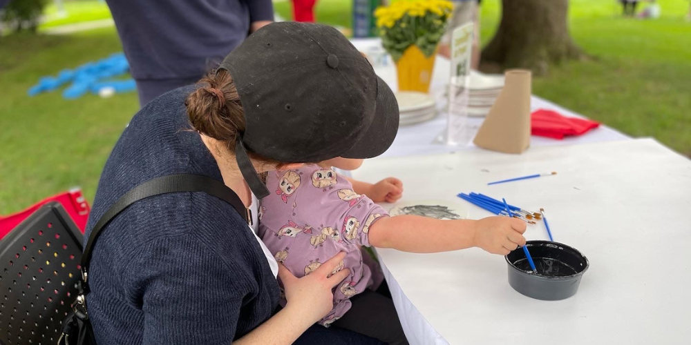 A mom has a baby on her lap, painting