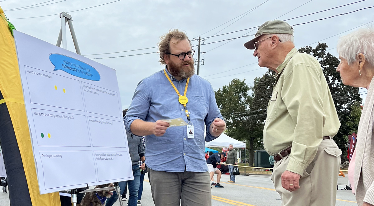 library staff talking to two residents beside a chart on an easel