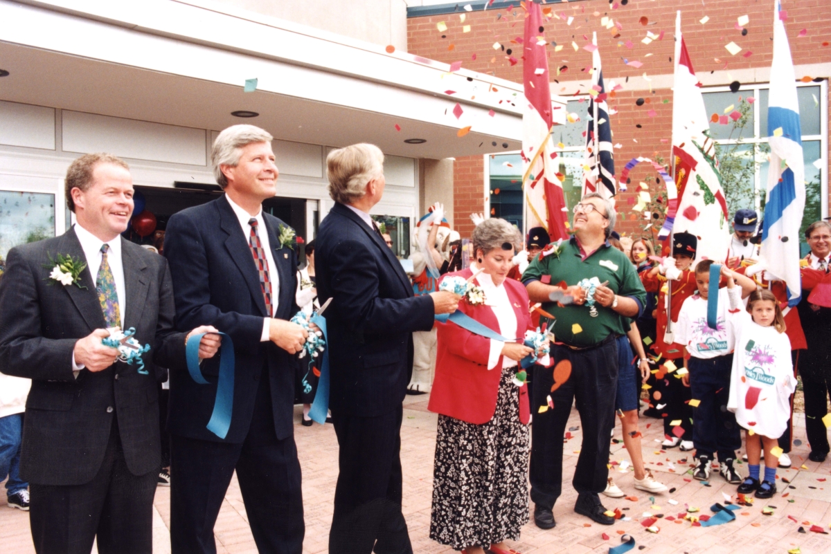 group of people holding scissors and cutting a blue ribbon