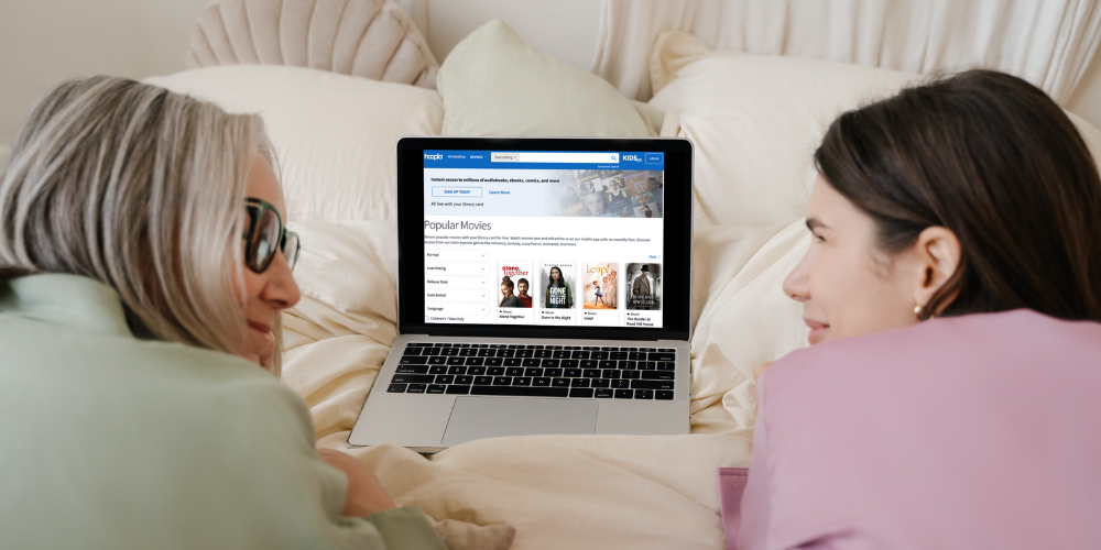 mom and daughter watching a movie together on a bed