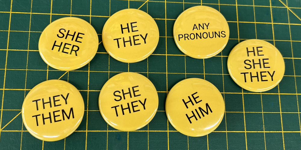 seven yellow button with various pronouns printed on them