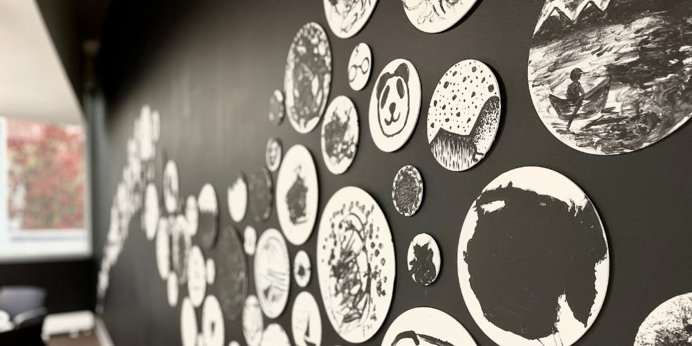  A black wall with black and white circular paintings on it.