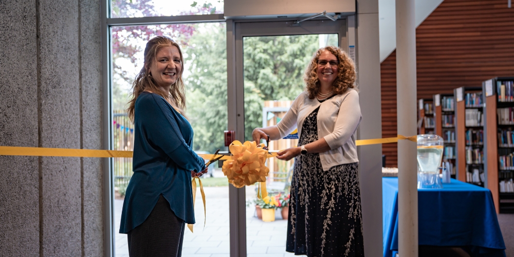 Lita Barrie and Jennifer Tarnawski cut a yellow ribbon strung across the door to the reading garden