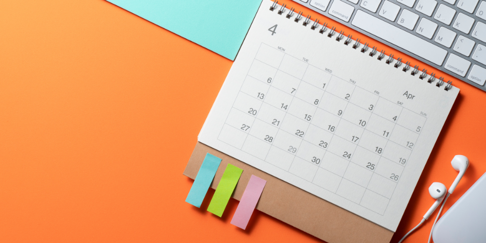 orange background with computer keyboard and paper calendar in foreground