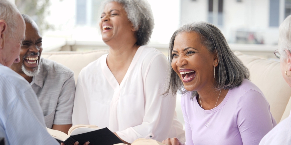 A group of older adults laughing with books in their hands