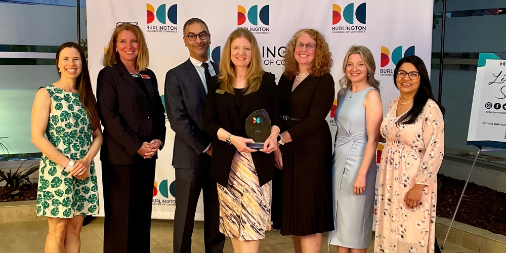 BPL board members, CEO, and directors stand in front of a photo backdrop holding an award