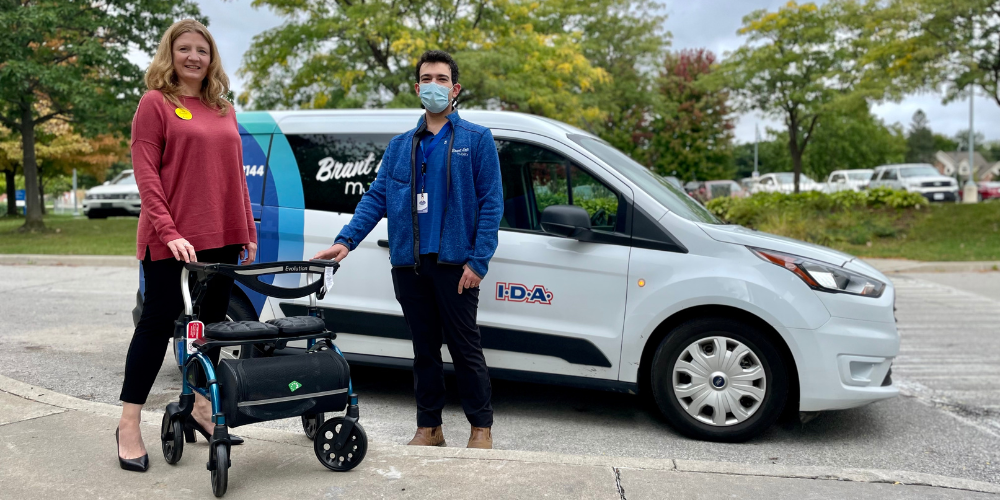 Lita Barrie receives a rollator from Mitchell Koplowitz in front of the Brant Arts Mobility van