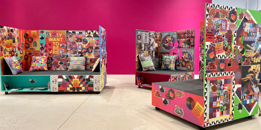 a large pink wall with three study carrels in front. The carrels are covered in bright images and stickers.