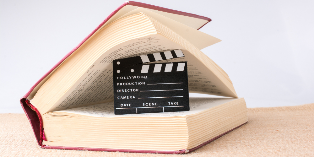 A minimalist photo of an open book with a film clapboard showing from the middle