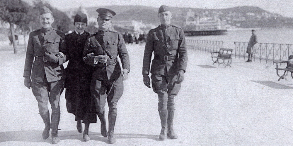 Nursing Sister Ethel Cutter of the American Red Cross on leave in France, 1918, walking with three soldiers
