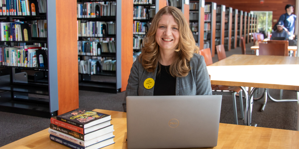BPL chief executive officer, Lita Barrie, smiles at the camera from behind a laptop.