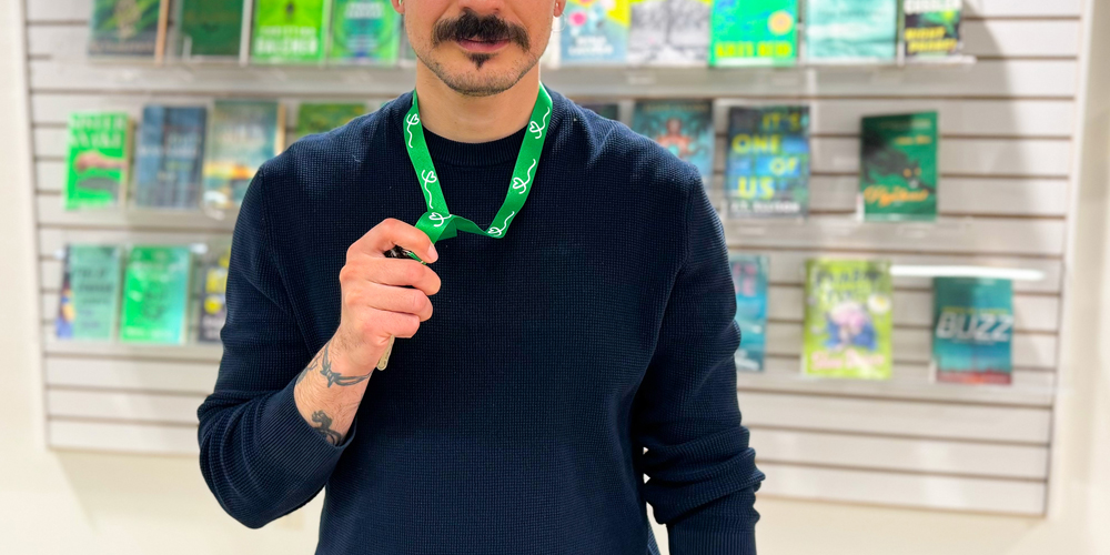 adult wearing a green lanyard standing in front of a book display