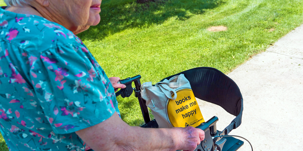 older adult  with book bag using walker