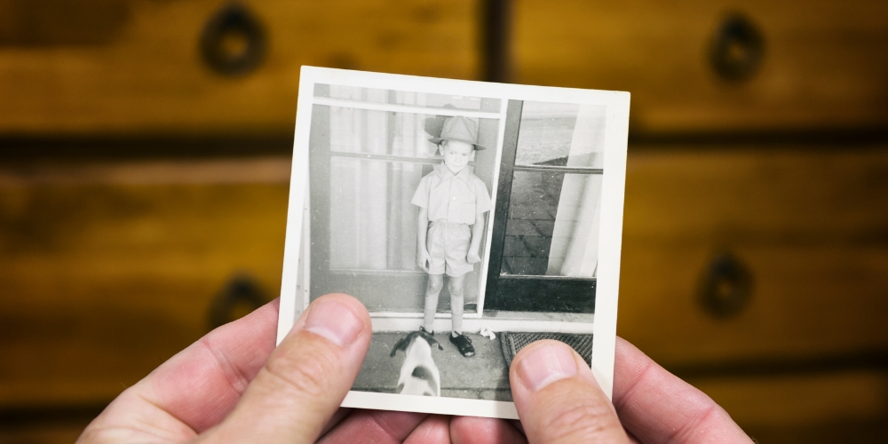 hands holding a black&white photo of a young boy and dog