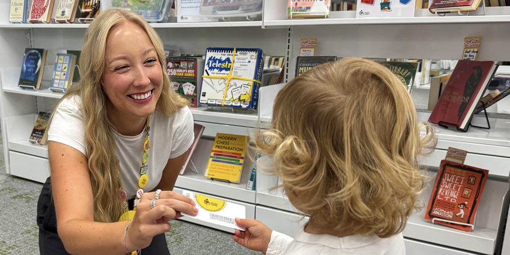 staff member handing a BPL card to a young child