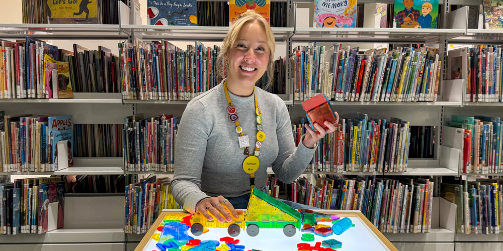 librarian sitting at a light table with various toys